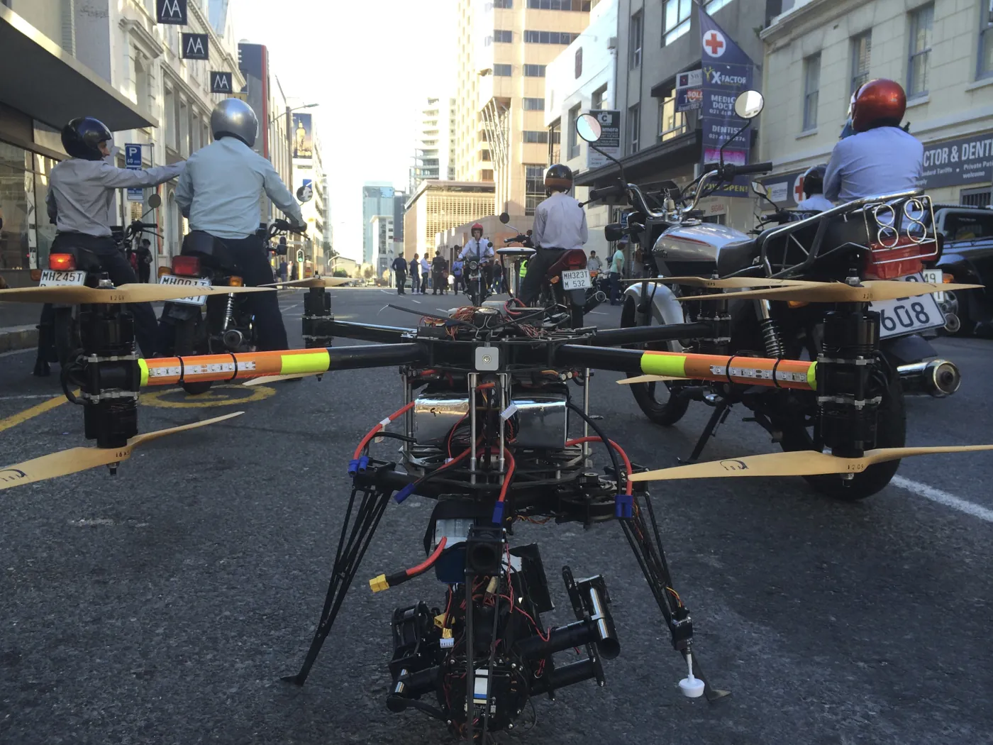 Skyhook's heavy-lift octocopter with a gimbal camera on a closed Cape Town street, motorbike riders waiting behind