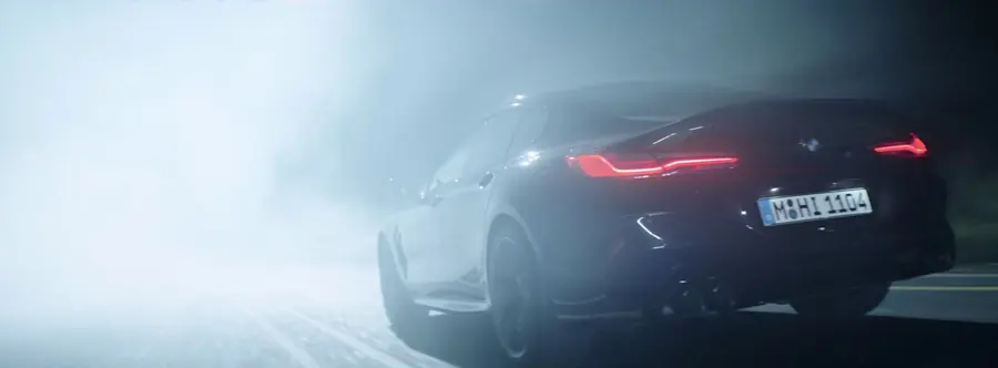 BMW M8 rear three-quarter in thick fog, lit from above