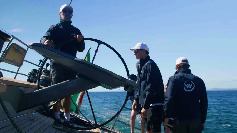 Helmsman at the wheel with crew alongside