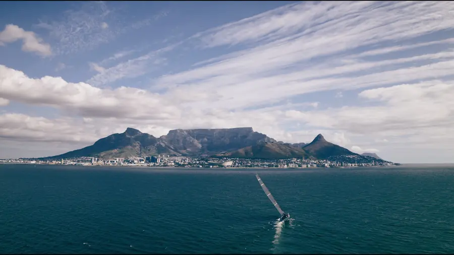 Wide shot of the yacht in Table Bay with Table Mountain behind